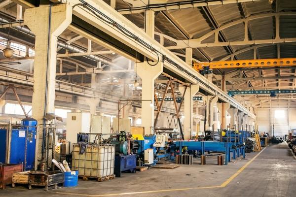 Operario utilizando un vehículo eléctrico industrial BKL Cargo para el transporte rápido de componentes en el pasillo de una planta de fabricación.
